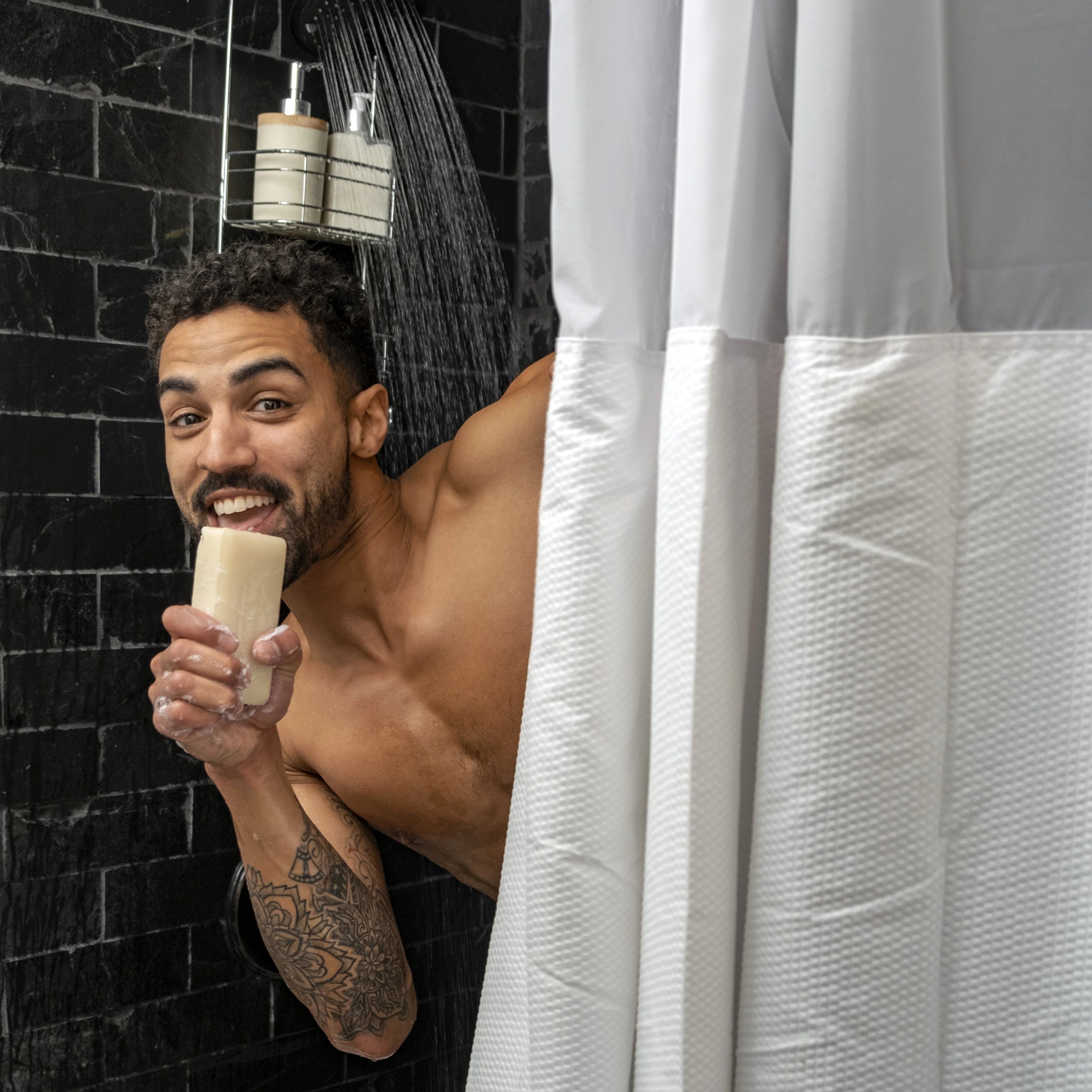 Male model peeking around a shower curtain and singing with a Man Bar soap