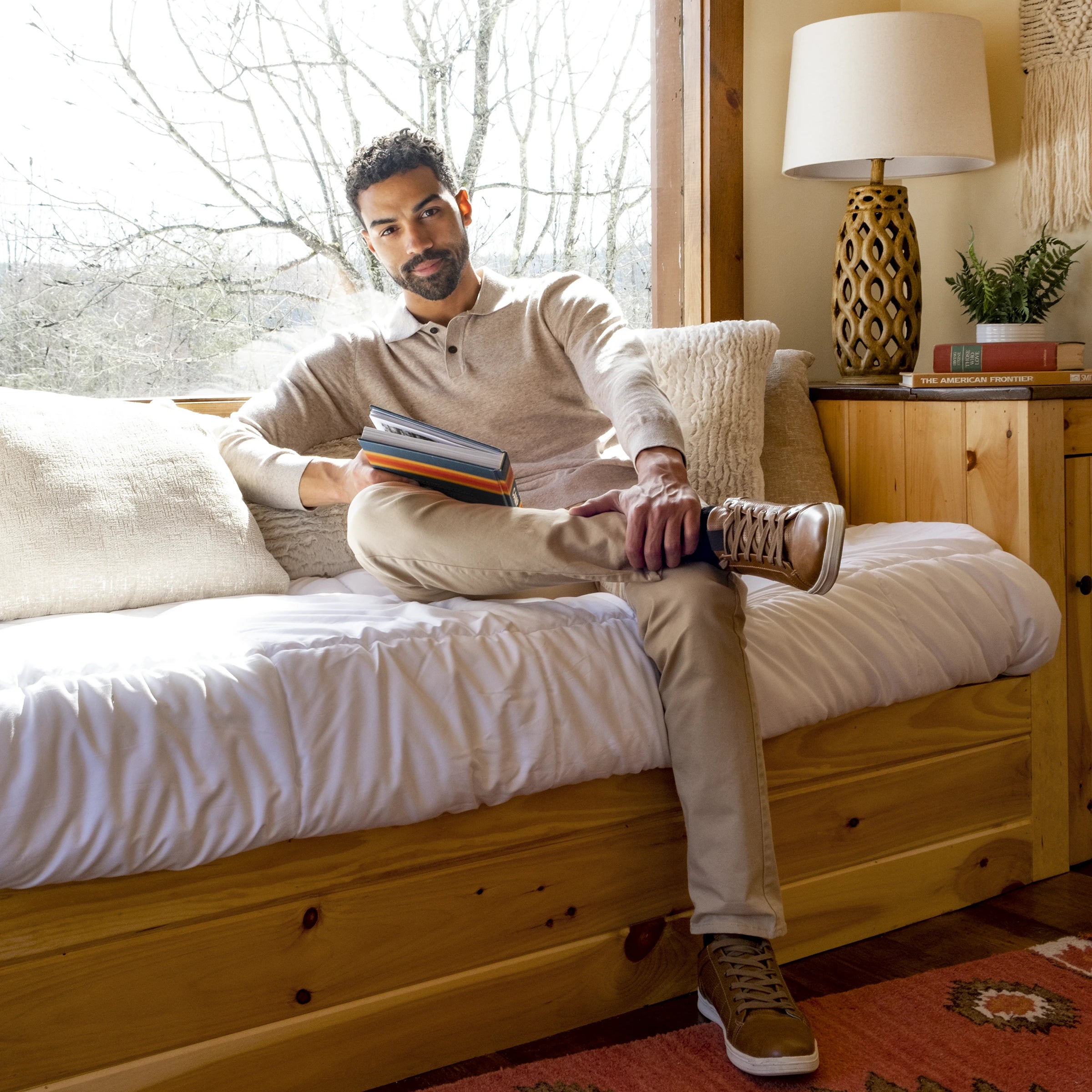 Male model sitting by a window with a book