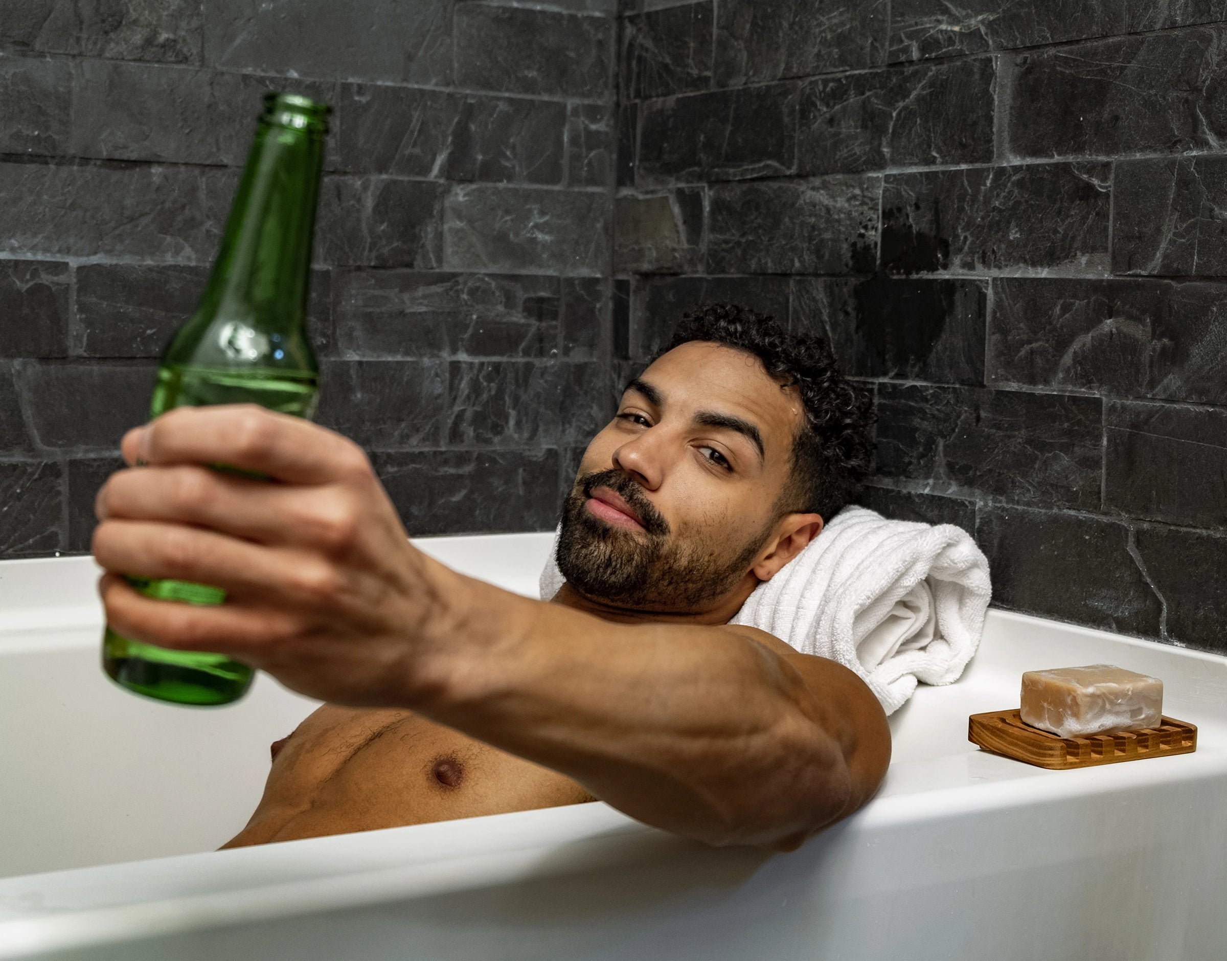 Male model in a bath tub drinking a beer